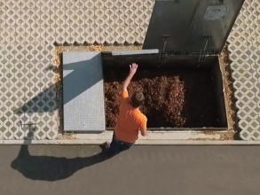 Mann in orangefarbenem T-Shirt öffnet ein Bodenlager mit Holzhackschnitzeln.
