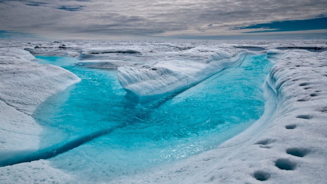 Aquamarinblaues Wasser sammelt sich im Vordergrund auf einer Schneefläche zu einem See.